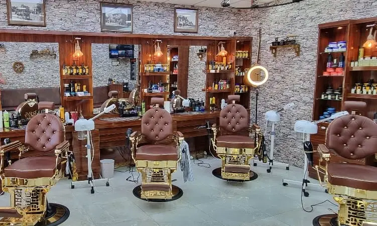 Interior with gold and brown leather barber chairs facing a stone wall and timber stations
